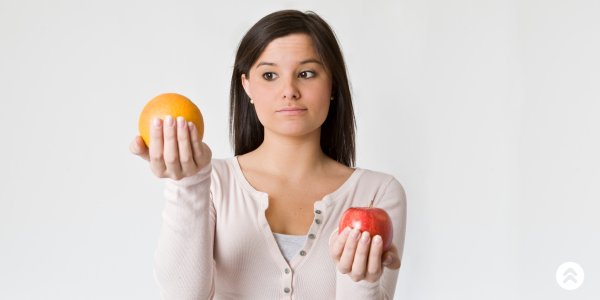 Woman comparing an apple and orange